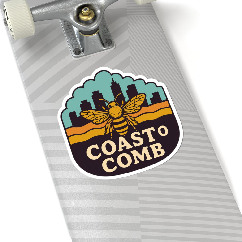 Skateboard with a 'Coasto Comb' sticker featuring a bee design on a white background