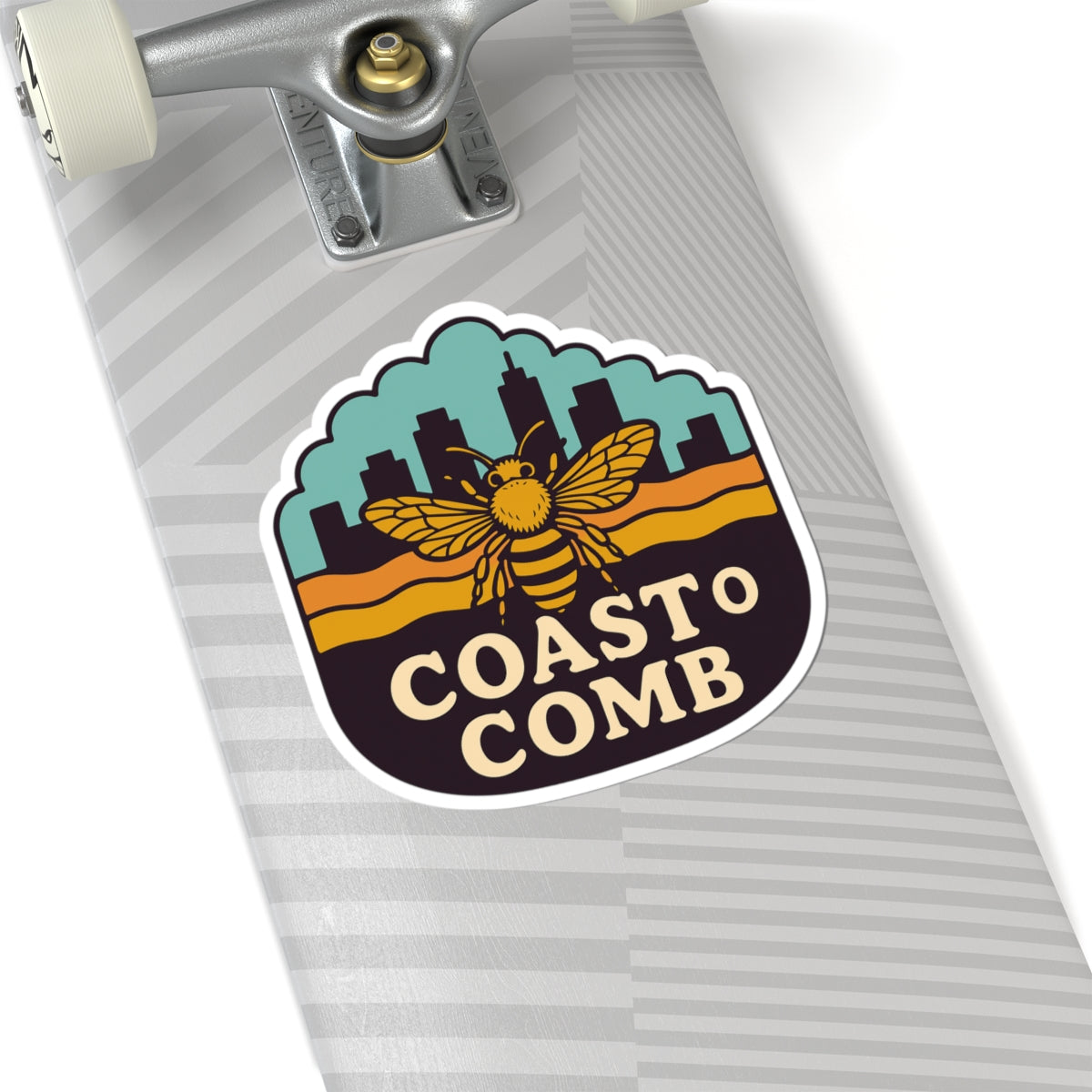 Skateboard with a 'Coasto Comb' sticker featuring a bee design on a white background