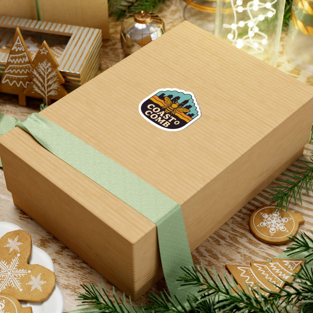 Gift box with a green ribbon and 'Coast to Coast' logo on a festive background with cookies and Christmas decorations.
