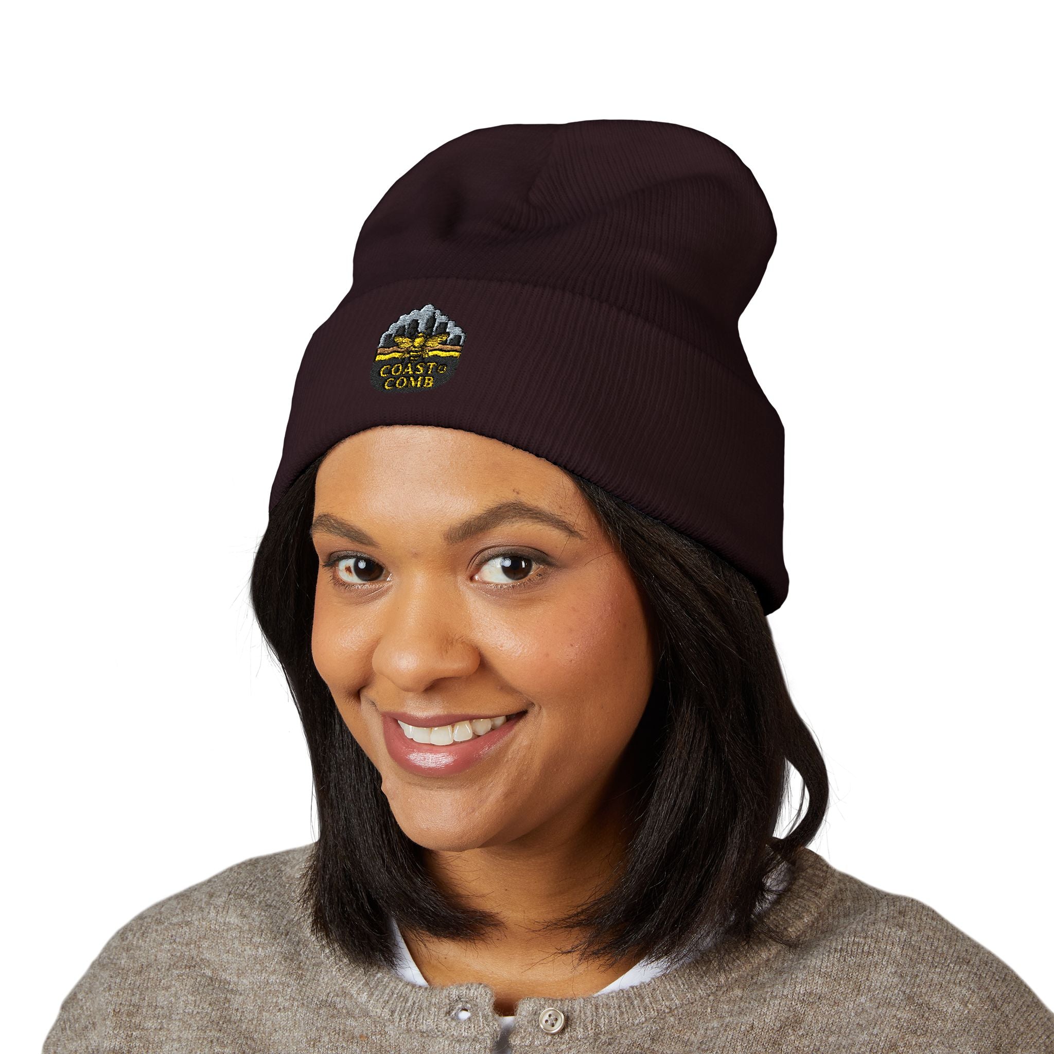 Woman wearing a dark brown beanie with a logo on a white background