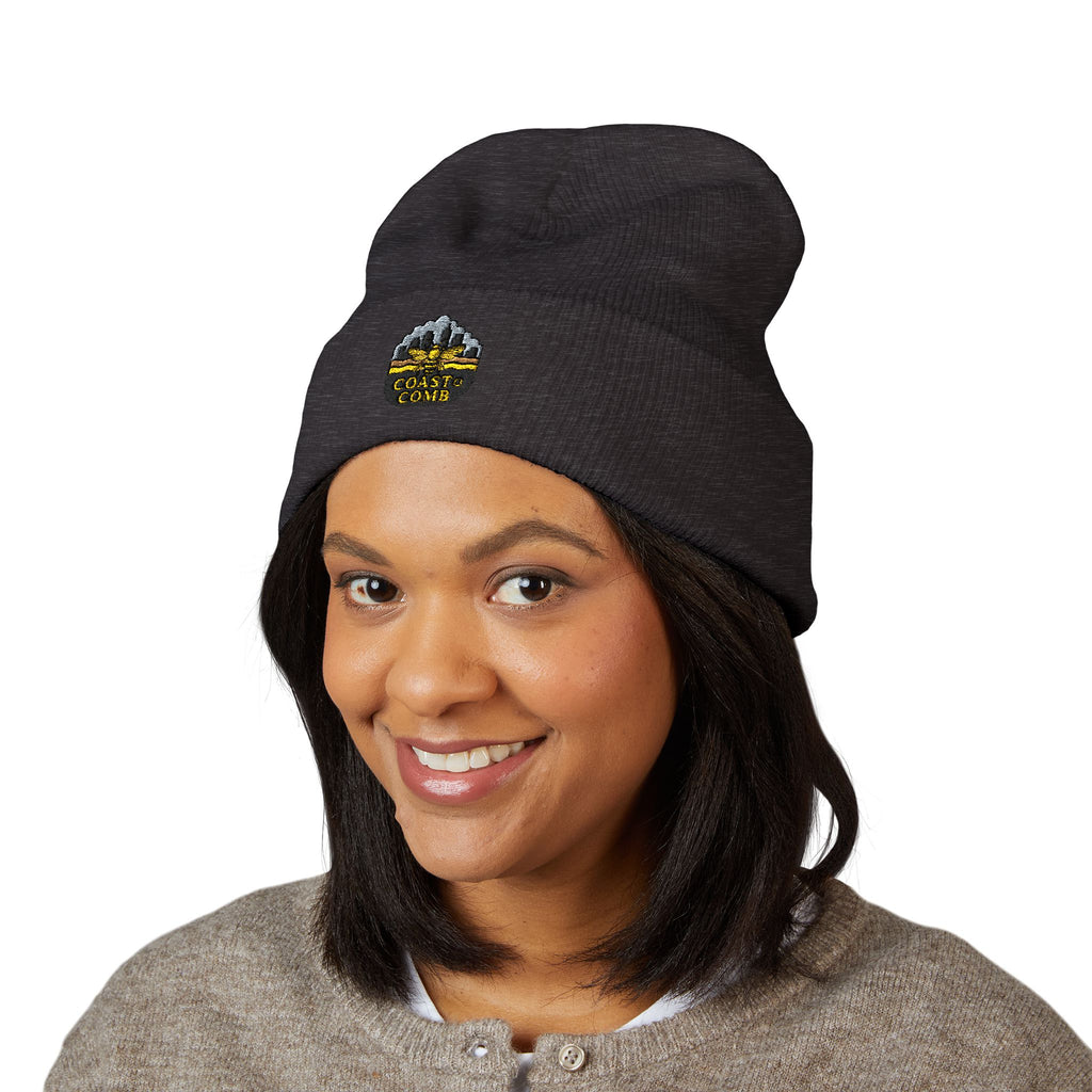 Person wearing a black beanie with a logo on a white background