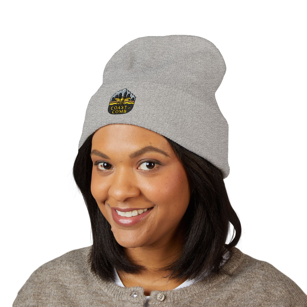 Person wearing a gray beanie with a logo on a white background