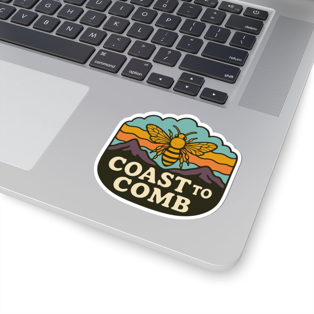 Coast to Comb sticker on laptop. Sticker includes picture of honeybee and mountains. 